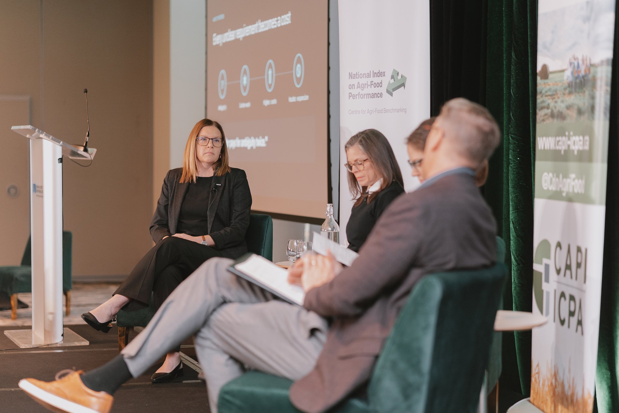 Tracy Gromniski seated on stage with other session participants at the CAPI Exchange Conference